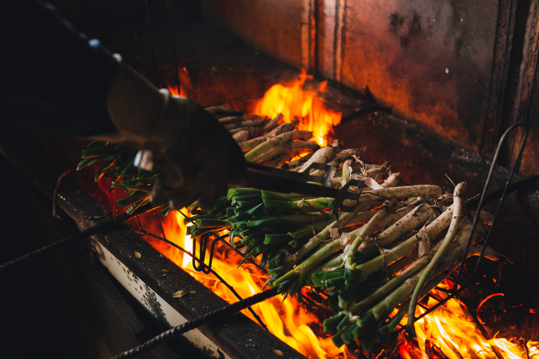 Charring Curd over a open grill a person using tongs to flip it