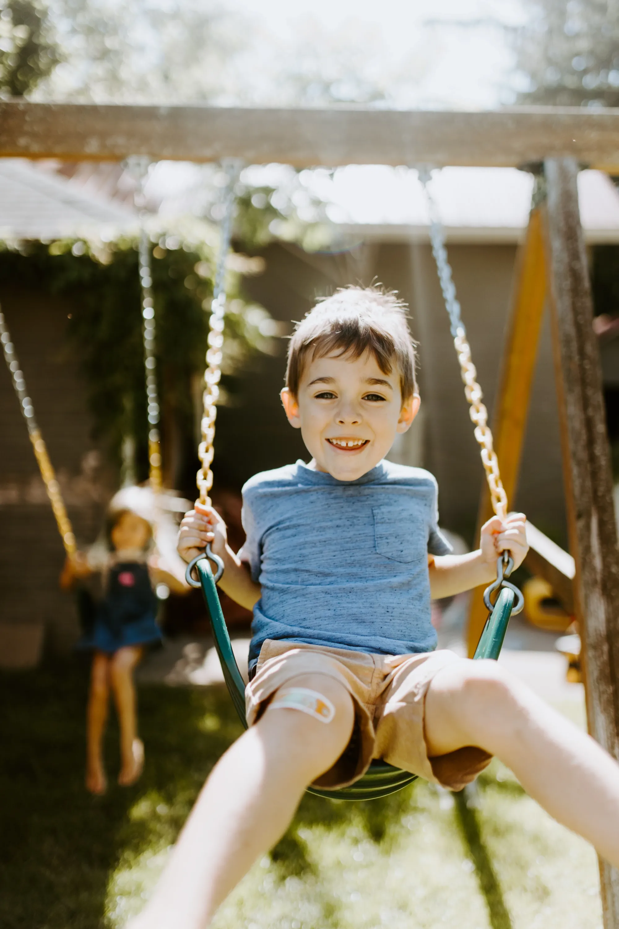 Two Children on a summer day swinging on their swings with big smiles.