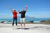 Two seniors jumping on a beach after spending time doing the best rebounding exercises.