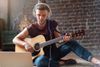 man playing guitar wearing headphones for guitar amp